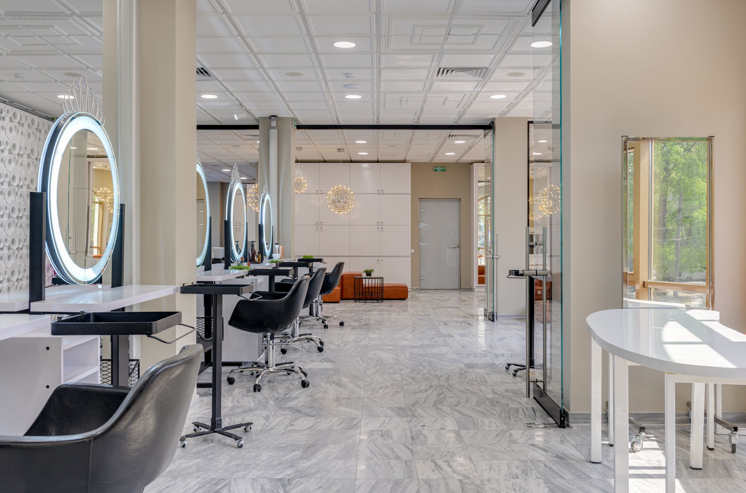 Sunlit styling stations with round illuminated mirrors inside the Velina salon