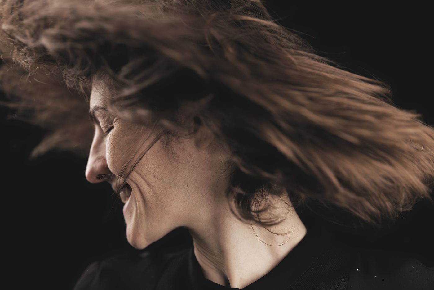 Close-up portrait of a guest laughing with her hair caught mid-motion